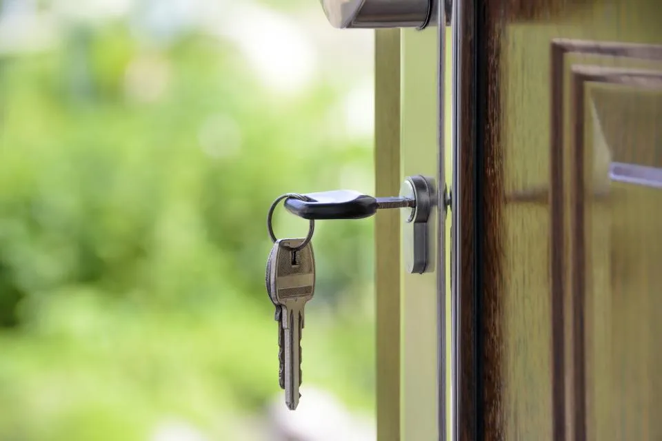 A set of keys hanging from the lock of a half-open door