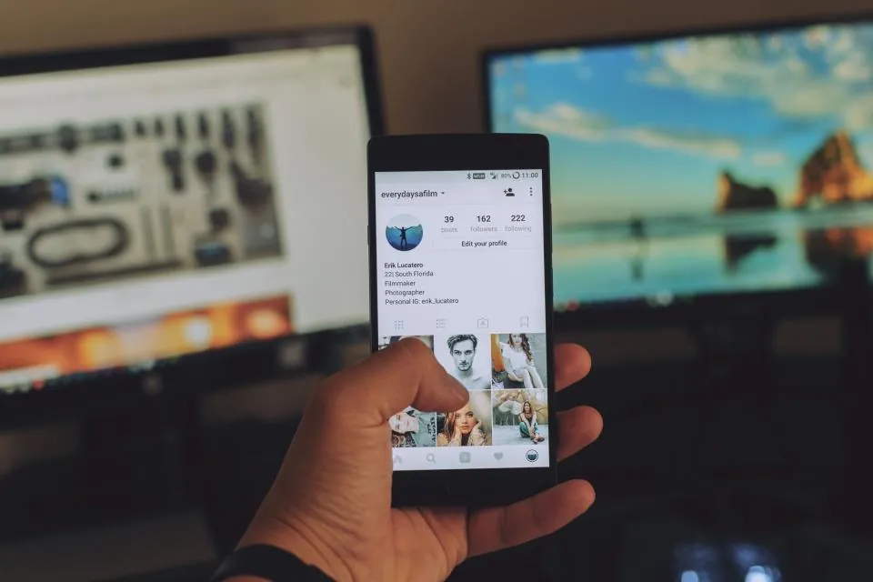 A hand holding a phone showing an Instagram profile