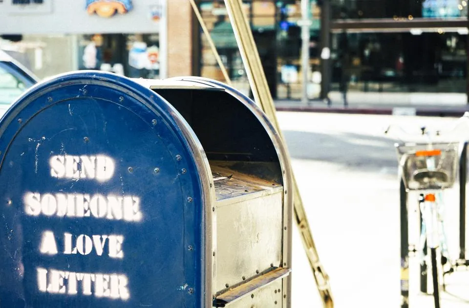 A blue mailbox painted with the words send someone a love letter
