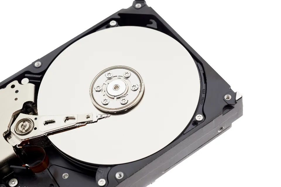An open hard drive showing its shiny platter and read arm